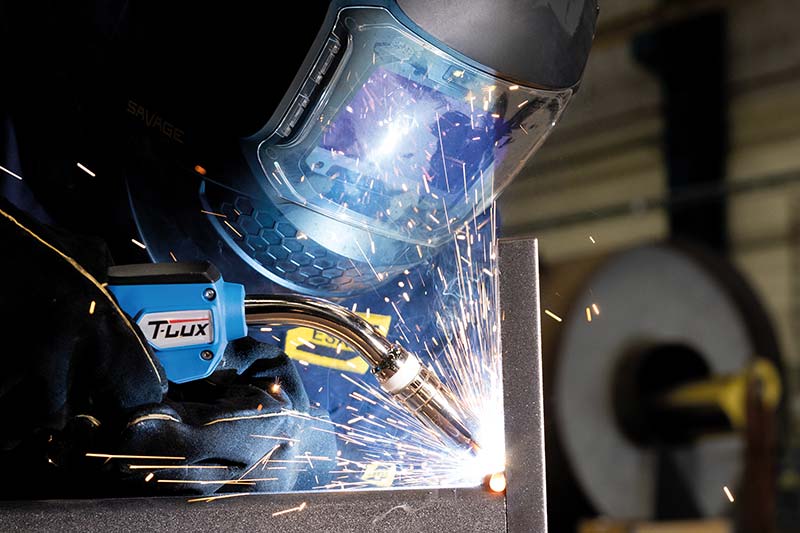 Industrial welder operating TBi T-Lux MIG/MAG welding torch during fabrication – high-performance torch for precision welding.